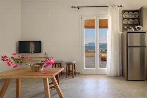 un soggiorno con tavolo e frigorifero di Κalamitsi Rooms & Apartments a Kimolos