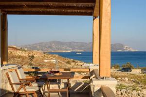 - une table et des chaises sur une terrasse avec vue sur l'océan dans l'établissement Κalamitsi Rooms & Apartments, à Kimolos