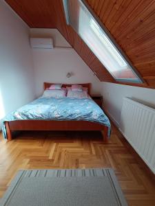 a bedroom with a bed in a attic with a window at SZEKI Apartman in Gyula