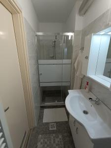 a white bathroom with a shower and a sink at SZEKI Apartman in Gyula