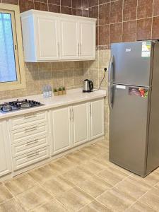 a kitchen with white cabinets and a stainless steel refrigerator at شقق التوحيد in Al Madinah