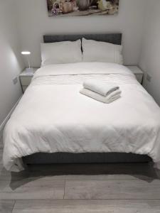 Una cama blanca con dos toallas encima. en Oceanik, en Dublín