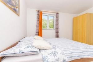 Un dormitorio con una cama con almohadas y una ventana. en Apartments Mira, en Starigrad-Paklenica