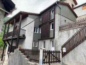 a building with a fence and stairs in front of it at L'Antre II : Maison cosy / Ambiance chalet. in Mauléon-Barousse
