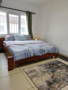 a bedroom with a bed with a window and a rug at Beach Road Oasis in Takoradi