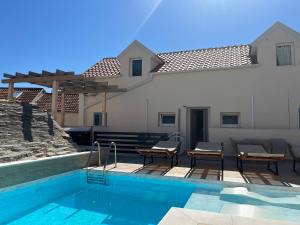 a swimming pool with chairs and a house at Villa de blue 2 in Bol