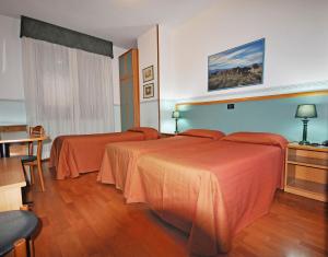 una camera d'albergo con due letti con lenzuola arancioni di Hotel Elisa a Porto Torres