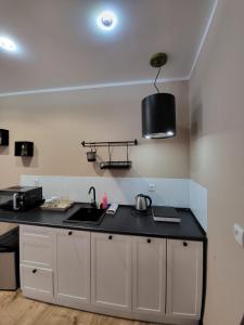 a kitchen with white cabinets and a black counter top at Willa przy Czarnej Bramie in Kłodzko