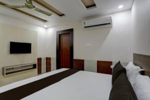 1 dormitorio con 1 cama y TV en la pared en OYO Anusuya Hotel en Bhubaneshwar