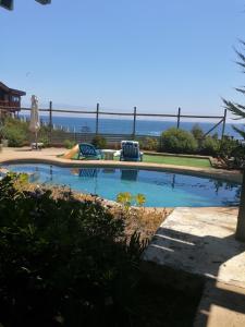 - une piscine avec deux chaises et l'océan en arrière-plan dans l'établissement CasaMar ElQuisco, à El Quisco