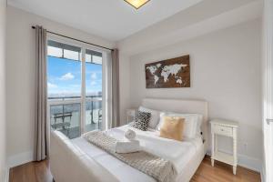 a white bed in a room with a large window at Rare 1BR - Rooftop Pool, Next to MTCC & CN Tower in Toronto