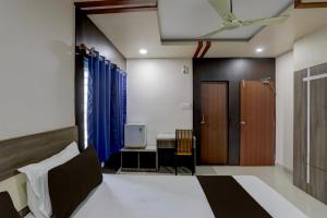1 dormitorio con cama, escritorio y puerta en OYO Anusuya Hotel en Bhubaneshwar