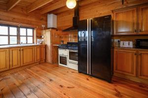 kuchnia z czarną lodówką i drewnianymi szafkami w obiekcie Reindeer Lodge by StayStaycations 