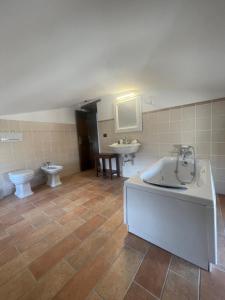 a bathroom with a tub and a toilet and a sink at LocAle Guest House in Pietralunga