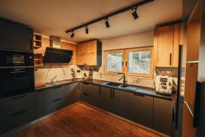 a kitchen with black appliances and wooden cabinets at The Cozy Chalet in Bosanski Petrovac