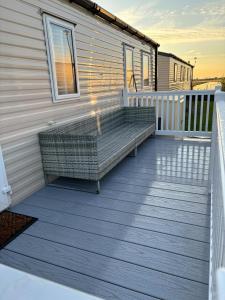 a deck with a bench on the side of a house at 3 bed Stunning caravan situated nr Whitstable in Whitstable