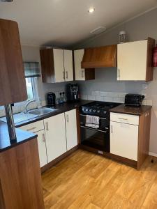 a kitchen with white cabinets and a black stove top oven at 3 bed Stunning caravan situated nr Whitstable in Whitstable