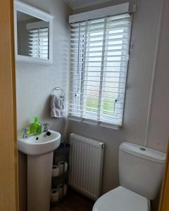 a bathroom with a toilet and a sink and a window at 3 bed Stunning caravan situated nr Whitstable in Whitstable