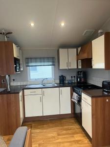 a small kitchen with white cabinets and a sink at 3 bed Stunning caravan situated nr Whitstable in Whitstable