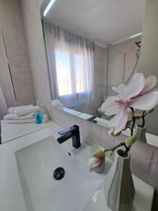 un bagno con lavandino bianco e un fiore in un vaso di Mi casita del norte a Mogro