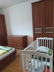 ein Schlafzimmer mit einem Kinderbett, einer Kommode und einem Bett in der Unterkunft PIKK Trenčianske Teplice in Trenčianske Teplice