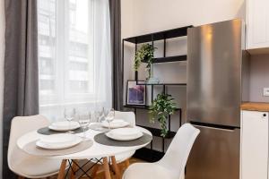 eine Küche mit einem Tisch mit weißen Stühlen und einem Kühlschrank in der Unterkunft Moonlight Studio Stary Mokotow in Warschau