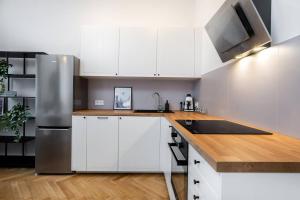 eine Küche mit weißen Schränken und einem Kühlschrank aus Edelstahl in der Unterkunft Moonlight Studio Stary Mokotow in Warschau