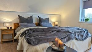 a bedroom with a large bed with two candles on a table at Hüs bi Söl - Haus bei Sylt in Uphusum