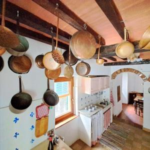 セッジャーノにあるantica abitazione con vista montagna Casa Normaの天井に多くの鍋やフライパンが掛けられたキッチン