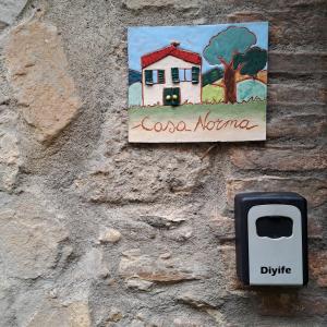 a sign for a house on a stone wall at antica abitazione con vista montagna Casa Norma in Seggiano