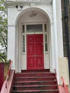 a red door on a white house with stairs at Comfy studio in London