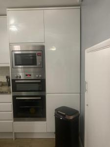 a kitchen with a microwave oven and a trash can at Modern Spacious 2 Bed Apartment **Free WIFI & Parking** in Goodmayes