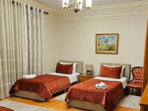 a bedroom with two beds and a chair at All Seasons Apartments in Shkodër