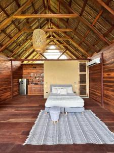 ein Schlafzimmer mit einem Bett in einem Holzgebäude in der Unterkunft Cabaña Vista al Mar Tayrona, A/C in Los Naranjos