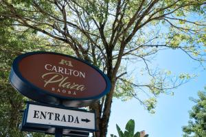 a sign for a restaurant in front of a tree at Carlton Plaza Baobá in Taubaté