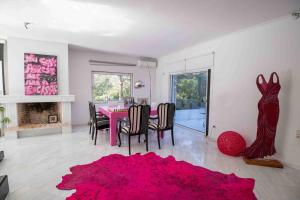 ein Esszimmer mit einem rosa Tisch und einem roten Teppich in der Unterkunft Dreamy relaxing secluded Villa Aurora in Palaia Fokaia