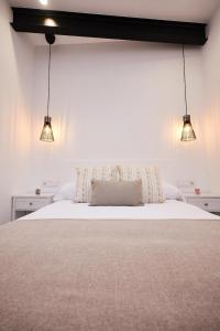 - une chambre avec un lit blanc et deux lumières dans l'établissement Villa Julia, à Ribadavia