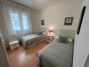 een slaapkamer met 2 bedden, een stoel en een raam bij Apartamento Fideo in Sevilla