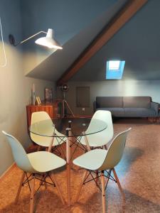 uma sala de estar com 4 cadeiras e uma mesa de vidro em Guest house Eça Agora! em Vila do Conde