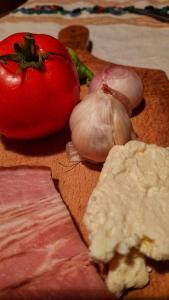 a cutting board with meat and a tomato and garlic at Sonja's House of Sun, Bislim Gorge, Riverview & yard in Kumanovo