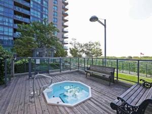 a hot tub on a deck with a bench and a building at Spacious 1BR - Downtown - Pool - Gym - Parking in Toronto