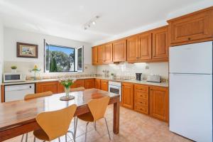 a kitchen with a wooden table and a white refrigerator at Villa Sea Garden Holidays in Port d'Addaia