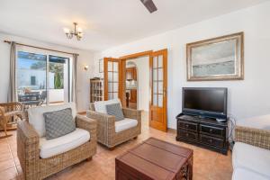 a living room with a flat screen tv and chairs at Villa Sea Garden Holidays in Port d'Addaia