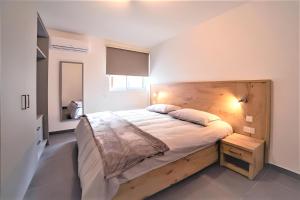 - une chambre avec un grand lit et une tête de lit en bois dans l'établissement Elise Apartments, à Il-Gżira