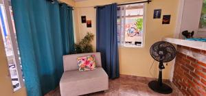 Zimmer mit einem Ventilator und einem Stuhl mit Kissen in der Unterkunft Posada Cedar Valley in Providencia