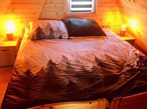 ein Bett mit einer Decke mit Bäumen darauf in einem Zimmer in der Unterkunft Wzgórze w Cieniu Lasu in Łukowica