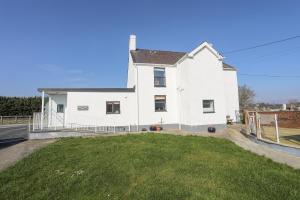 a white house with a green yard at Bryn Afon Farm in Caernarfon