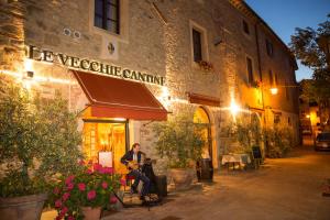 a woman sitting on a bench in front of a restaurant at Le Vecchie Cantine in Chianni