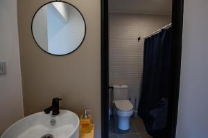 La salle de bains est pourvue d'un lavabo, d'un miroir et de toilettes. dans l'établissement Bomar Lodge, à Puertecillo