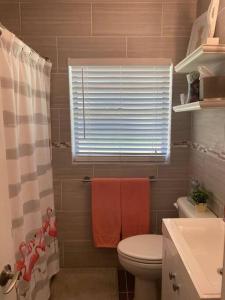 a bathroom with a toilet and a window with towels at Chic 3BR Home w/ Big Yard in Winter Park-Orlando in Orlando